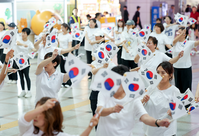 ▲&nbsp;제80주년 광복절을 나흘 앞둔 지난 11일 오후 수원시 팔달구 수원역 대합실에서 열린 '광복, 그날의 기쁨 재현하다' 행사에서 권선구 주민자치 댄스 프로그램 수강생들이 태극기를 들고 플래시몹 공연을 하고 있다. /전광현 기자 maggie@incheonilbo.com