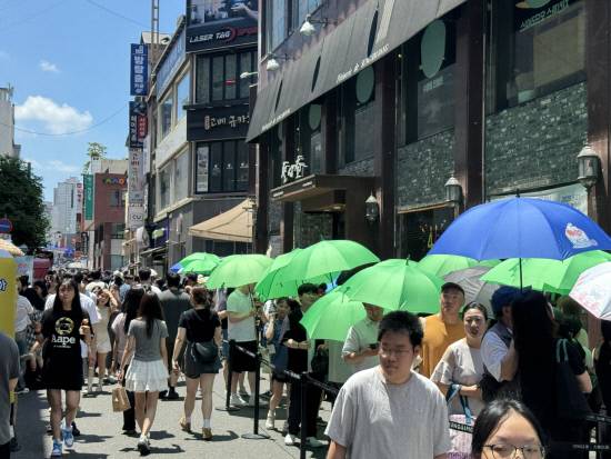 지난 6월 29일 대전 성심당 본점에서 빵을 사기 위해 많은 사람들이, 성심당에서 나눠준 녹색 우산을 쓰고 줄을 서 있다. 인근 거리 역시 인파로 북적였다.