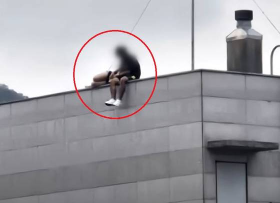 부산진구의 한 고층 건물 옥상 난간에 앉아 있는 남녀. 사진 JTBC ‘사건반장’ 캡처