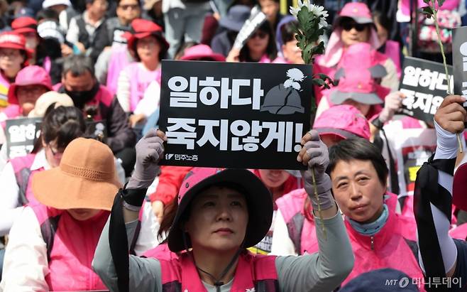 민주노총 조합원이 23일 오후 서울 중구 서울고용노동청 앞에서 열린 '작업중지권 쟁취! 노동자 참여 산업안전보건법 개정 민주노총 결의대회'에서 국화꽃과 손피켓을 들고 있다. 2025.4.23/사진=뉴스1  Copyright (C) 뉴스1. All rights reserved. 무단 전재 및 재배포,  AI학습 이용 금지.