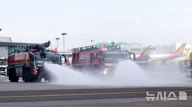 [서울=뉴시스] 김선웅 기자 = 12일 서울 강서구 김포국제공항 국내선 이동지역에서 한국공항공사 관계자들이 소방차를 이용해 폭염 대비 계류장 살수작업을 하고 있다. 살수작업은 활주로 등 이동지역 포장면의 표면온도가 60도 이상일 경우 물을 살포해 온도를 약 10도 가량 낮추어 포장 손상 위험을 줄이고 항공기 운항 안전성을 높이는 효과가 있다. 한국공항공사는 폭염경보가 발령될 경우 항공기 이동지역 포장면의 온도를 하루 세 차례 측정해 살수작업 여부를 결정한다. (공동취재) 2025.08.12. photo@newsis.com