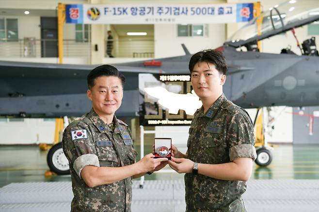 류기필 제11전투비행단장(왼쪽)이 이혁주 검사중대장에게 F-15K 주기검사 500대 달성 기념 코인을 전달하고 있다. 제11비 제공