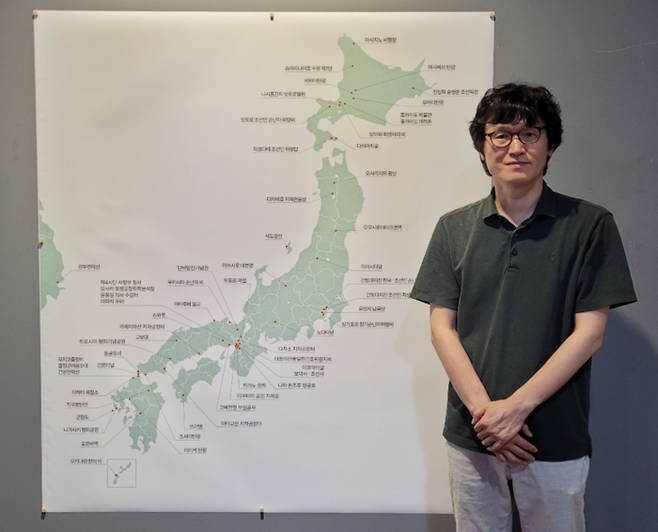 장용근 사진기록연구소장이 '잊혀진 이름 남겨진 자리-조선인 강제동원의 기록'展에 참여한 작가들의 일본 방문지 기록 지도 앞에서 포즈를 취하고 있다.<임훈기자 hoony@yeongnam.com>