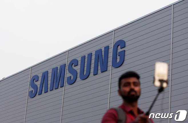 인도 노이다에 위치한 삼성 스마트폰 제조 공장 앞에서 한 남성이 휴대폰으로 사진을 촬영하고 있는 모습. 2018.07.09. ⓒ 로이터=뉴스1