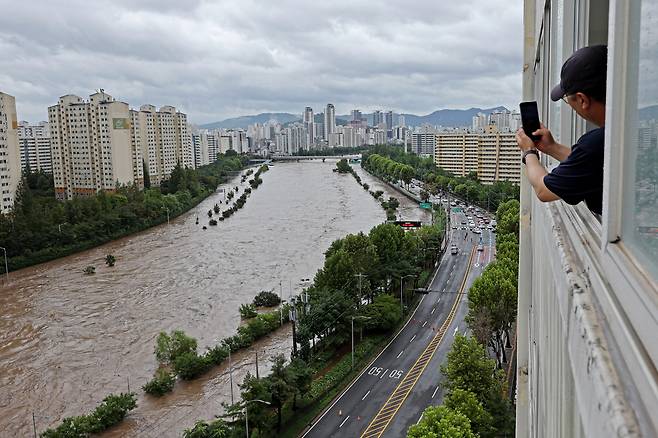 집중호우가 내린 13일 서울 노원구민이 월계1교 인근 범람한 중랑천과 통제된 동부간선도로를 사진으로 기록하고 있다./연합뉴스