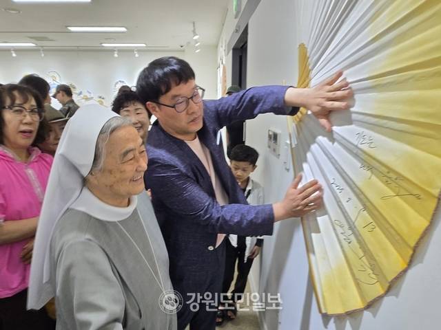 ▲ 이해인 수녀가 13일 양구 인문학박물관을 방문, 전시장에 놓인 부채에 서명을 한 뒤 환하게 웃고 있다.