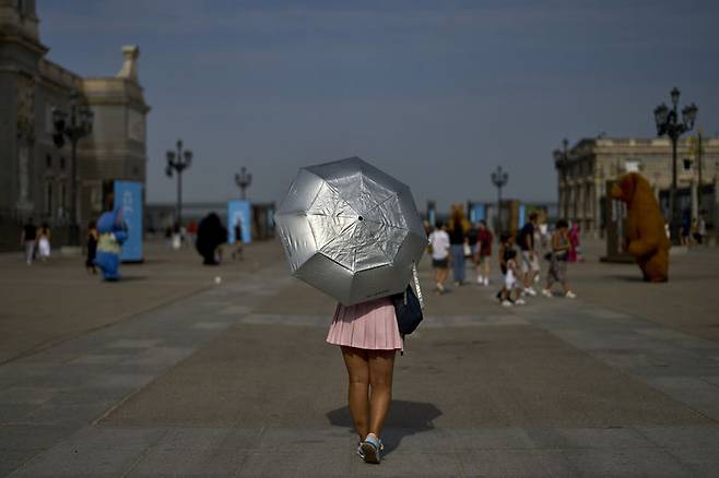 [마드리드=AP/뉴시스] 12일(현지 시간) 스페인 마드리드에서 한 여성이 양산을 쓴 채 이동하고 있다. 2025.08.13.