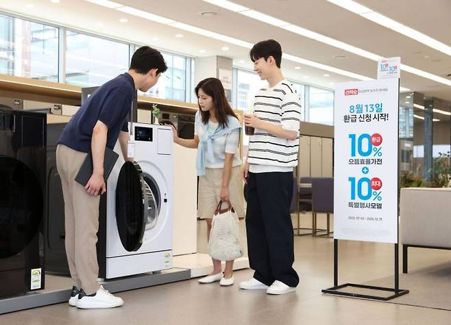 삼성전자 모델이 에너지 소비효율 1등급의 '세탁건조기'와 '에어컨' 제품의 설명을 듣고 있다. 사진=삼성전자