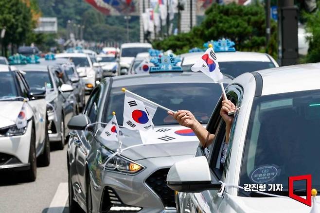 지난해 광복절을 이틀 앞두고 서울 송파구 올림픽로에서 태극기로 장식한 택시를 탑승한 독립유공자 가족이 태극기를 흔들고 있다. 강진형 기자