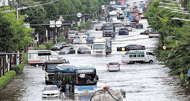 오늘도 200㎜ 쏟아진다… 폭우, 수도권 강타 - 13일 인천 서구 일대 도로가 물에 잠겨 차량들이 서행하고 있다. 이날 인천 서구와 경기 일부 지역에선 일 강수량이 200㎜가 넘기도 했다. 이 여파로 경인전철 주안역~부평역 구간 상하행선 열차 운행이 중단됐다가 1시간여 만에 재개됐다. 인천국제공항에선 53편의 항공기가 지연 운항했다. 경기 김포시에선 갑자기 쏟아진 장대비에 차량이 떠내려가는 사고가 발생해 80대 운전자가 사망했다. 기상청에 따르면 14일까지 수도권 지역 예상 강수량은 50~200㎜다. /인천일보