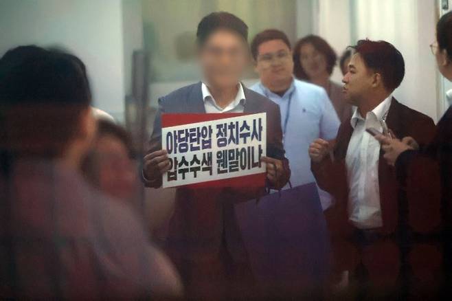 김건희 특검팀이 국민의힘 당사에 대한 압수수색에 나선 13일 서울 여의도 국민의힘 중앙당사에서 당 관계자가 항의 피켓을 들고 있다. 뉴시스