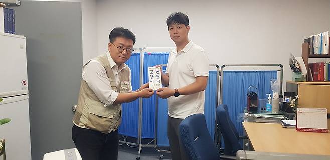 윤범기 전국언론노조 MBN지부장(왼쪽)이 노조 집행부가 모금한 동물병원비 후원금을 이 기자에게 전달하고 있다. /MBN지부 제공
