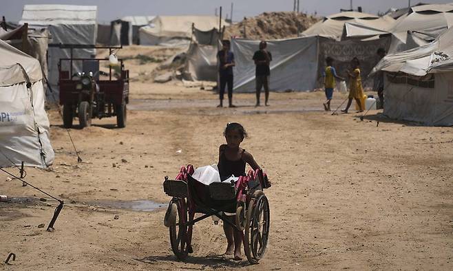13일(현지시간) 가자지구의 한 난민 캠프에서 팔레스타인 소녀가&nbsp;물을 실은 수레를 밀고 있다.&nbsp;AP연합뉴스