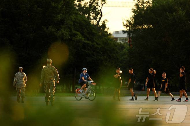 미국 군인들이 14일 워싱턴DC의 한 거리에서 운동하는 사람들 근처를 지나가고 있다. 도널드 트럼프 미국 대통령은 워싱턴DC 메트로폴리탄 경찰청의 연방 관할권을 발표하고, 수도의 범죄 예방을 돕는다는 명목으로 주 방위군을 배치했다. 2025.8.14 ⓒ 로이터=뉴스1 ⓒ News1 강민경 기자