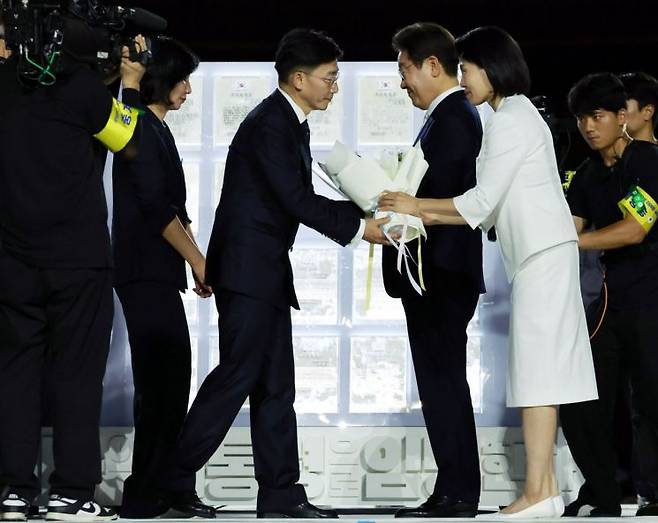 이재명 대통령과 김혜경 여사가 15일 서울 세종대로 광화문광장에서 열린 제21대 대통령 국민임명식 '광복 80년, 국민주권으로 미래를 세우다' 행사에서 국민 대표인 이국종 국군대전병원장으로부터 '빛의 임명장'을 받고 있다. 연합뉴스