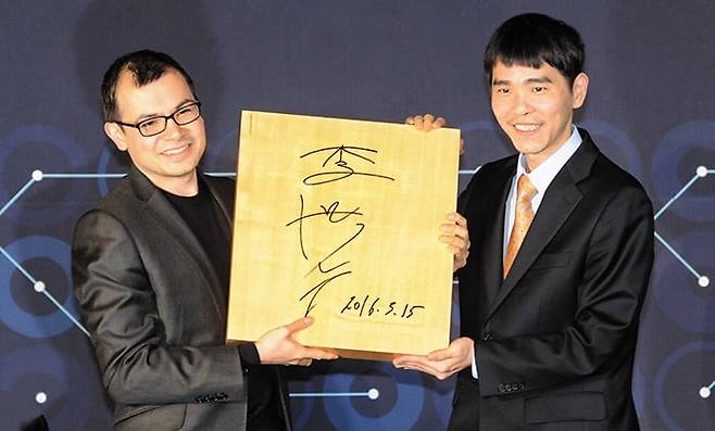 2016년 3월 서울에서 구글 딥마인드의 데미스 허사비스(왼쪽) 최고경영자가 인공지능(AI) 알파고로 이세돌 9단과의 대결에서 승리한 후 이 9단의 사인이 담긴 바둑판을 선물받으며 웃고 있다. 허사비스는 AI의 다음 과제로 단백질 구조 예측을 선택했고 2024년 노벨화학상을 받았다. 이세돌은 바둑계를 떠났다. /김지호 기자