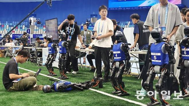 15일 세계휴머노이드로봇대회에의 5대5 축구 종목 참가자가 경기에 앞서 로봇을 점검하고 있다. 베이징=김철중 특파원 tmf@donga.com