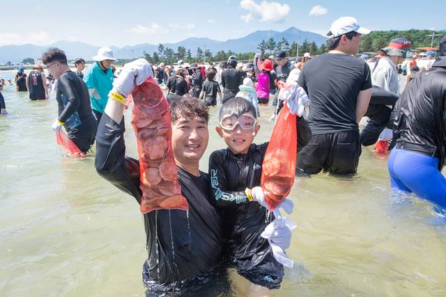 ▲ 최북단 고성군 죽왕면 백도해수욕장을 찾은 피서객들이 갓 잡아 올린 싱싱한 가리비와 조개를 들어 보이며 즐거워하고 있다.