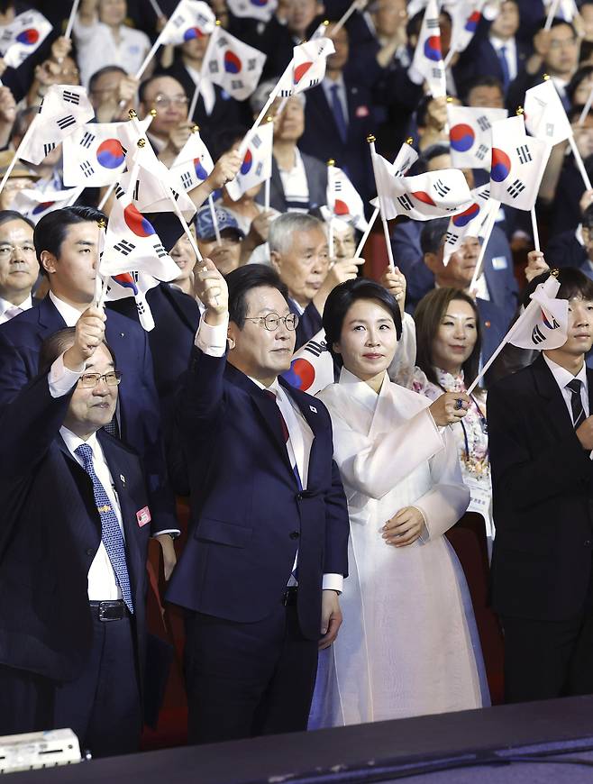 President Lee Jae Myung (second from left, front row) and first lady Kim Hea Kyung (third from left, front row) waves the national flag during the 80th anniversary of the National Liberation Day on Friday in Seoul. (Pool photo via Yonhap)