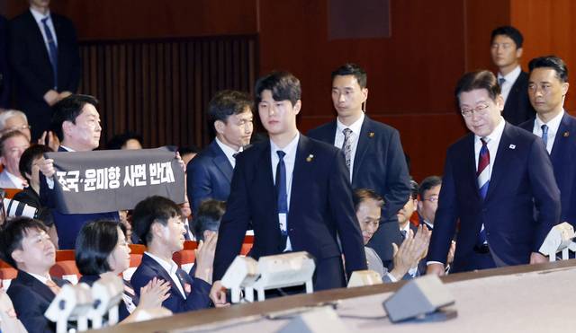 국민의힘 안철수 의원이 15일 서울 세종문화회관에서 열린 80주년 광복절 경축식에서 이재명 대통령이 경축사를 마치고 자리를 향할 때 ‘조국·윤미향 사면 반대’라는 문구가 적힌 펼침막을 들어보이고 있다. 연합뉴스