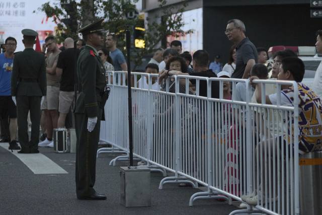 9일 중국 베이징에서 중국 준군사경찰이 전승절 80주년 열병식 리허설을 준비하기 위해 장안대로 인근 상점가를 폐쇄하는 동안 방문객과 관광객들이 바리케이드에 서서 지켜보고 있다. AP연합.