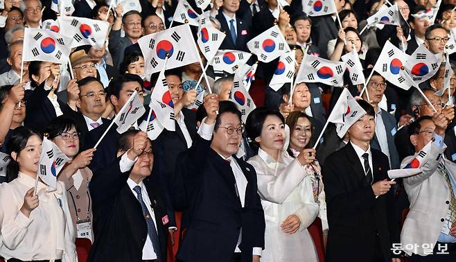 이재명 대통령과 김혜경 여사가 15일 서울 세종문화회관에서 열린 제80주년 광복절 경축식에서 만세삼창을 한 뒤 태극기를 흔들고 있다. 이 대통령은 경축사에서 “현재 북측의 체제를 존중하고 어떠한 형태의 흡수통일도 추구하지 않을 것”이라며 “우리 정부는 실질적 긴장 완화와 신뢰 회복을 위한 조치를 일관되게 취해 나갈 것”이라고 밝혔다. 이 대통령 왼쪽은 이종찬 광복회장. 송은석 기자 silverstone@donga.com