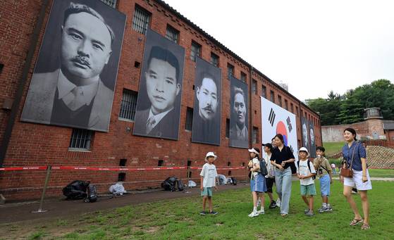15일 서울 서대문형무소 역사관을 찾은 어린이들과 관람객들이 대형 태극기와 독립운동가들의 얼굴이 담긴 현수막 앞을 지나고 있다. [뉴스1]
