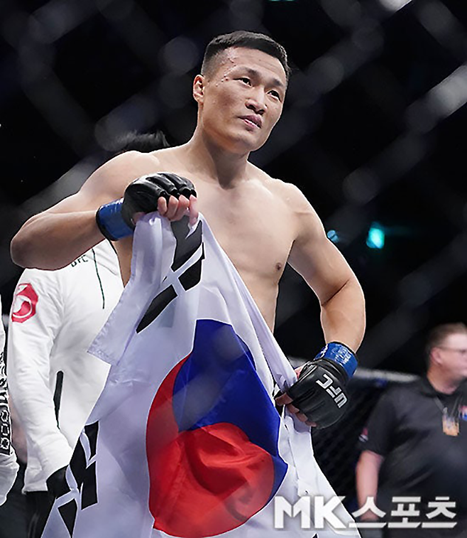 ‘코리안 좀비’ 정찬성이 2019년 12월 대한민국 부산광역시 사직실내체육관 1만651명 앞에서 제4대 UFC 라이트급 챔피언 프랭키 에드거를 1라운드 3분 18초 펀치 TKO로 꺾은 후 태극기를 펼치고 있다. 사진=김영구 기자