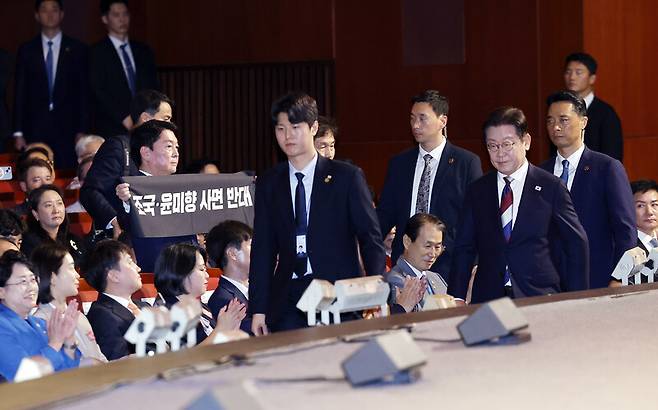 안철수 국민의힘 의원이 15일 서울 세종문화회관에서 열린 80주년 광복절 경축식에서 이재명 대통령이 경축사를 마치고 자리로 향할 때 ‘조국·윤미향 사면 반대’라는 문구가 적힌 펼침막을 들어 보이고 있다. 연합뉴스