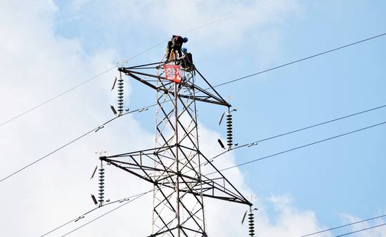 Staff from the Korea Electric Power Corporation (Kepco) repair a pylon in Nonsan, South Chungcheong, on Oct. 14, 2021. [JOONGANG ILBO]