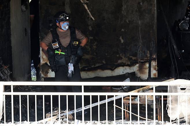 A forensic investigator inspects the apartment building in Changjeon-dong, Mapo District, western Seoul, where a fire broke out on Aug. 17. [NEWS1]