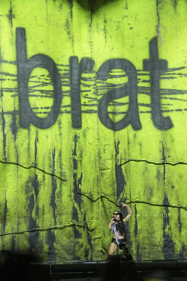 [서머셋=AP/뉴시스] 찰리 XCX가 영국 페스티벌 글랜스턴베리에서 사용한 연둣빛 무대 장치에 '브랫(BRAT)'이란 문구가 새겨져 있다.