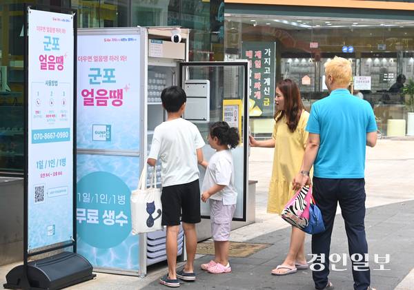 무더운 날씨가 이어진 18일 오후 군포시 산본로데오거리에 설치된 무인 냉장고 ‘군포 얼음땡’에서 시민들이 물을 가져가고 있다. 2025.8.18 /최은성기자 ces7198@kyeongin.com