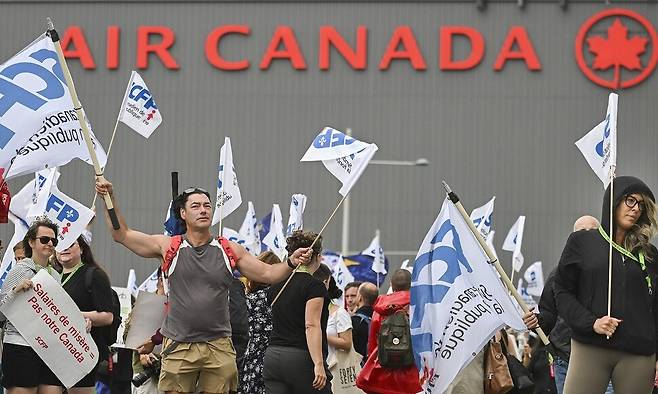 17일(현지시각) 캐나다 몬트리올의 에어캐나다 본사 앞에서 사람들이 시위를 벌이고 있는 모습. 연방 정부가 항공사와 승무원 노조 간의 분쟁에 개입해 강제 중재를 명령하고 운앙 재개를 지시한 것에 반발하고 하고 있다. AP연합뉴스