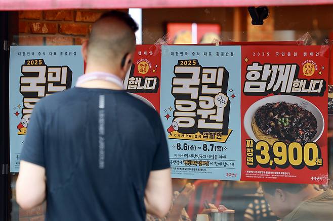 서울 시내 한 홍콩반점을 찾은 시민이 할인 행사 포스터를 보는 모습. [사진 = 연합뉴스]