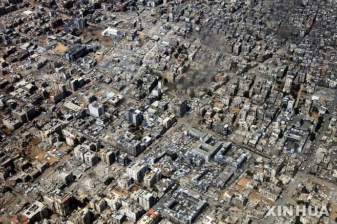 [가자지구=신화/뉴시스] 17일(현지 시간) 요르단 공군 수송기가  가자지구 상공에서 팔레스타인 주민들에게 전달한 구호물자를 공중 투하하는 가운데 가지구에서 연기가 피어오르고 있다. 이날 요르단은 약 106톤의 식량과 구호 물품을 가자지구에 투하했다. 2025.08.18.