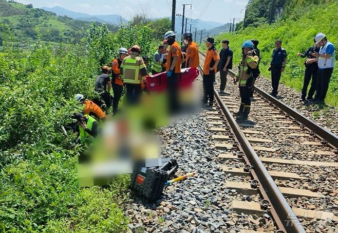 19일 오전 10시 52분쯤 경북 청도군 청도소싸움 경기장 인근 경부선 철로에서 마산으로 향하던 무궁화 열차가 선로에서 작업하던 근로자 7명을 치는 사고가 발생해 출동한 119구조대원이 부상자를 옮기고 있다.  (경북소방본부제공,재판매 및 DB금지) 2025.8.19/뉴스1 ⓒ News1