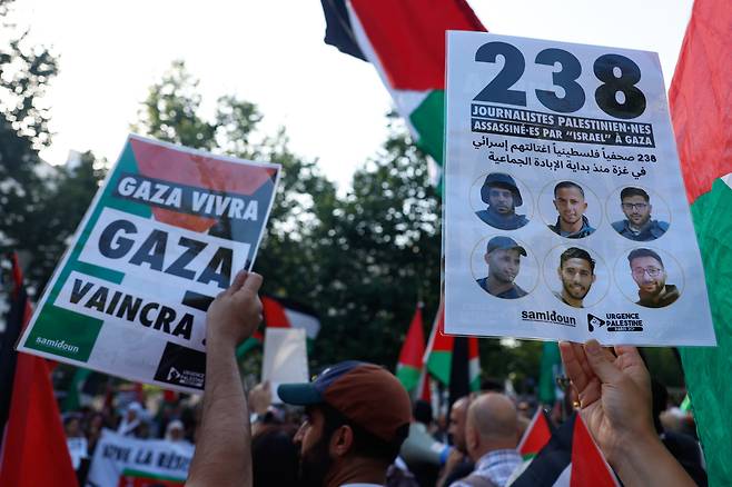 한 시위자(오른쪽)가 2025년 8월 12일 프랑스 파리에서 열린 가자지구와 팔레스타인을 위한 연대 집회에서 "238명의 팔레스타인 언론인이 대량학살이 시작된 이래로 이스라엘에 의해 암살당했습니다"라고 쓰인 플래카드를 들고 있다. /연합뉴스