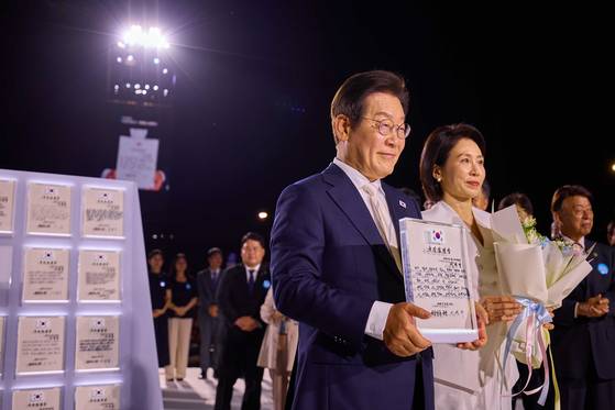 이재명 대통령과 김혜경 여사가 15일 서울 세종대로 광화문광장에서 열린 제21대 대통령 국민임명식 '광복 80년, 국민주권으로 미래를 세우다' 행사에서 '빛의 임명장' 큐브가 완성된 뒤 인사하고 있다. [사진 대통령실]