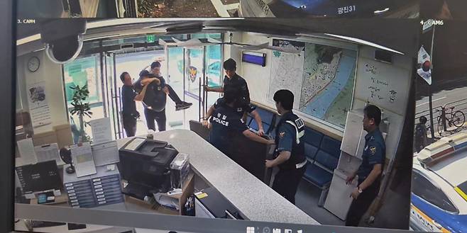 지난 12일 경찰관들이 버스에서 쓰러진 시민을 들고 서울 광진경찰서 광나루지구대로 도착한 모습. /사진제공=서울 광진경찰서.