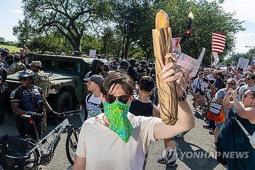 빵 시위 (워싱턴DC AFP=연합뉴스 자료사진) 2025년 8월 16일 미국 수도 워싱턴DC에서 시위 중인 한 시민이 빵을 들고 있다. 이는 세관국경보호국(CBP) 요원에게 호기 샌드위치를 던졌다는 혐의로 체포되고 면직된 전 법무부 공무원 찰스 숀 던(37)의 사건을 계기로 제작된 것으로 추정된다. (Photo by Alex Kent / GETTY IMAGES NORTH AMERICA / Getty Images via AFP) 2025.8.19.