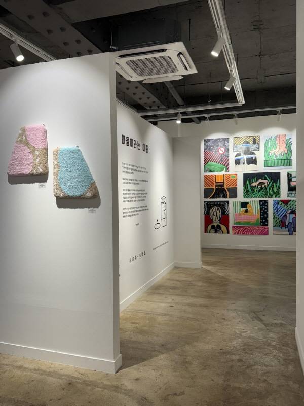 전시 '마을이라는 이름'의 입구 전경, 벽면 가득한 회화와 설치 작품이 관람객을 마을의 기억 속으로 안내한다. 안계미술관