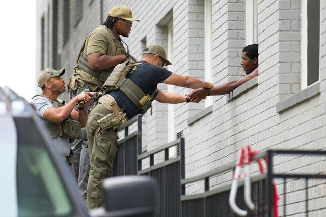 무장한 요원들이 19일 워싱턴 북서쪽 페트워스의 한 아파트에서 남성에게 수갑을 채우고 있다. 이 요원들이 입고 있는 셔츠에는 '워싱턴 현장 사무실'이라는 글씨와 함께 '경찰'이라는 글씨가 써 있다. 워싱턴=AP 연합뉴스