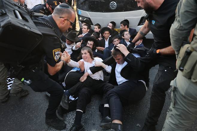이스라엘 군 징집 소식에…유대교인들 반대시위 19일(현지시간) 이스라엘 수도 텔아비브 인근 브네이 브락에서 고속도로를 막은 채 군 징집 반대 시위를 하고 있는 초정통파 유대교인들(하레디)을 경찰이 해산시키려 하고 있다. 이스라엘 대법원은 지난해 6월 만장일치로 정부가 초정통파 유대교인의 징집에 나서야 한다고 판결했다.  EPA연합뉴스