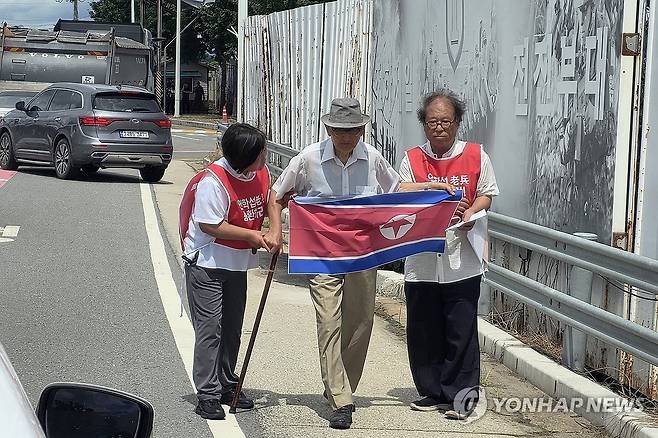 인공기 펼쳐 든 비전향장기수 안학섭 (파주=연합뉴스) 심민규 기자 = 20일 오전 경기도 파주시 통일대교 남단에서 북한 송환을 요구한 비전향장기수 안학섭 씨(가운데)가 인공기를 펼쳐 들고 있다. 2025.8.20 wildboar@yna.co.kr