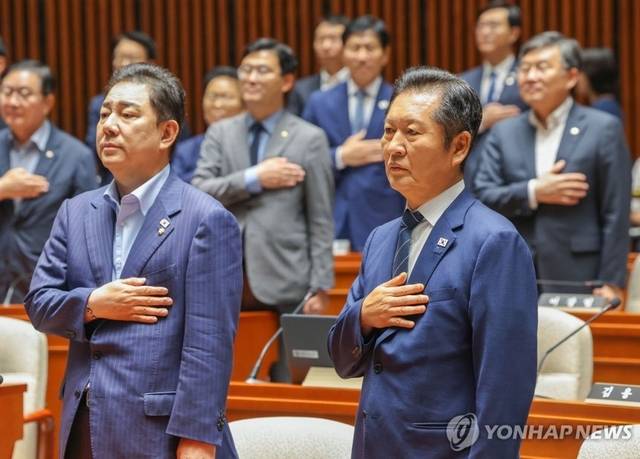 정청래(오른쪽) 더불어민주당 대표와 김병기 원내대표가 21일 국회에서 쟁점법안 처리를 위한 8월 임시국회 본회의 개회를 앞두고 가진 의원총회에서 국기에 경례하고 있다. [연합뉴스]