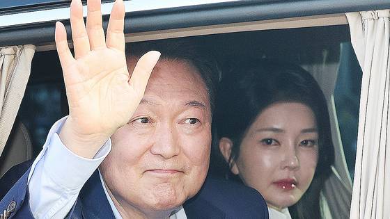 Ousted President Yoon Suk Yeol, left, waves his hand as he departs from his presidential residence in Yongsan District in central Seoul on April 11. His wife Kim Keon Hee is seen behind him in the car. [NEWS1]