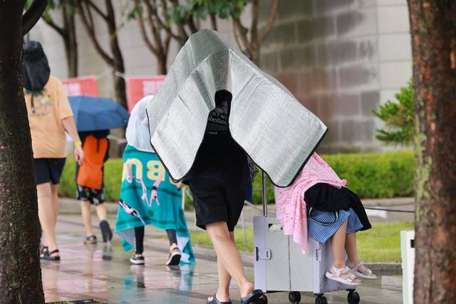 8일 소나기가 내린 서울 광화문광장 인근에서 한 가족이 돗자리로 비를 막으며 이동하고 있다. 연합뉴스