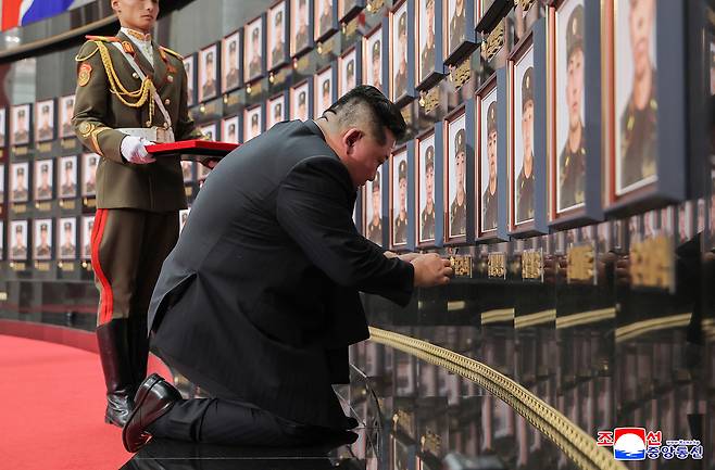 North Korean leader Kim Jong-un places "Hero of the Republic" medals on the portraits of fallen soldiers during a ceremony in Pyongyang to award state commendations to commanders and combatants deployed to Russia's war with Ukraine and to comfort the bereaved families of fallen soldiers, in this undated photo released by the North's official Korean Central News Agency on Friday. (Yonhap)