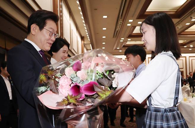 한일 정상회담을 위해 일본을 방문중인 이재명 대통령과 김혜경 여사가 23일(현지 시간) 일본 도쿄의 한 호텔에서 열린 재일동포 오찬 간담회에서 화동에게 꽃다발을 받고 있다. 2025.08.23. [도쿄(일본)=뉴시스]